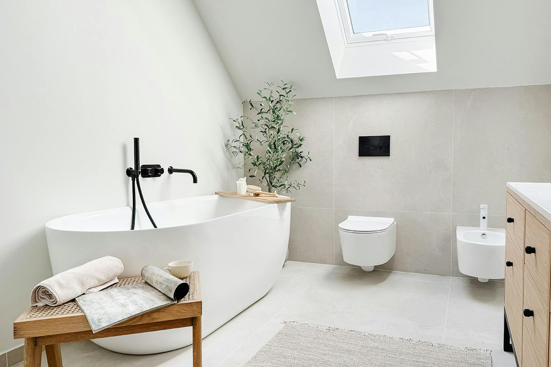 ovale Badewanne mit schwarzen Armaturen in einem minimalistischen Badezimmer in hellen Farben