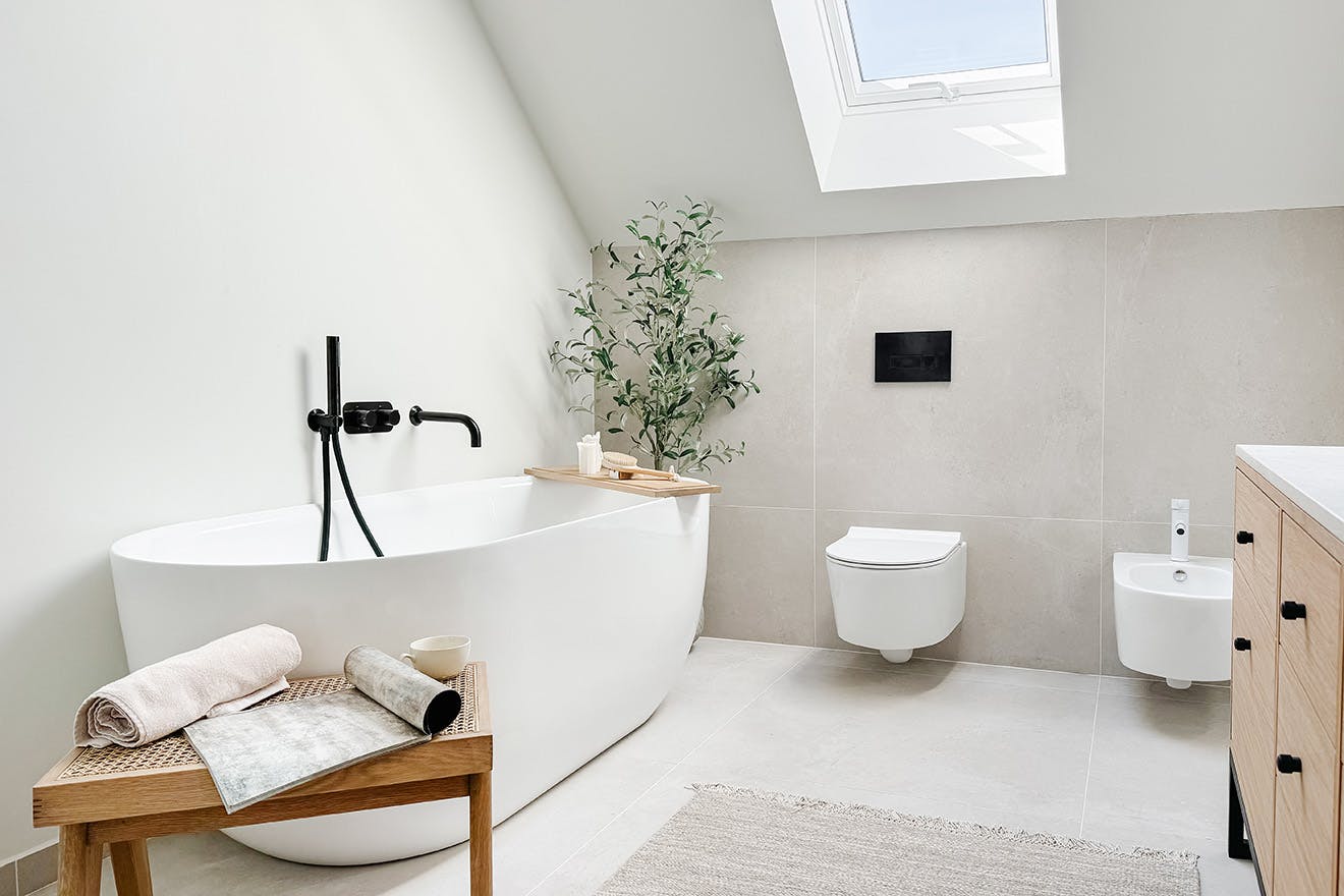 ovale Badewanne mit schwarzen Armaturen in einem minimalistischen Badezimmer in hellen Farben