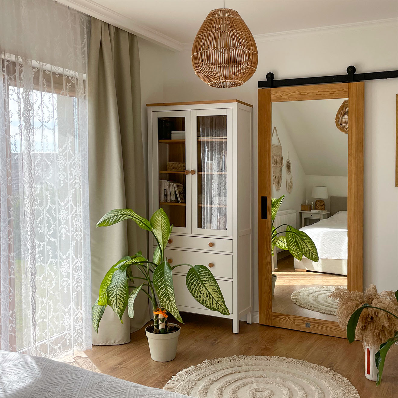 drzwi przesuwne z lustrem obok białej witryny z szufladami w sypialni z garderobą