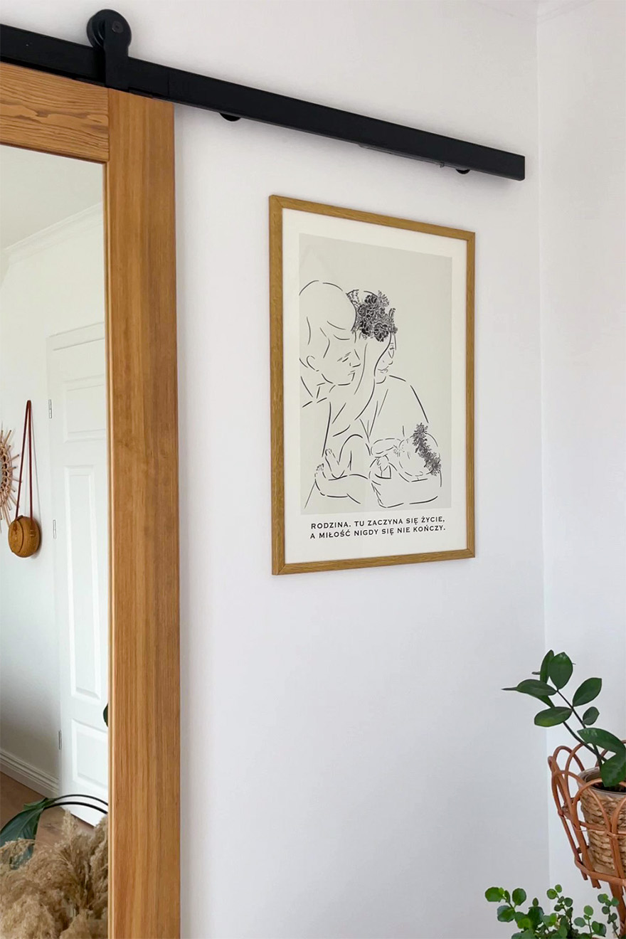 plakat w drewnianej ramie na ścianie obok drewnianych drzwi przesuwnych