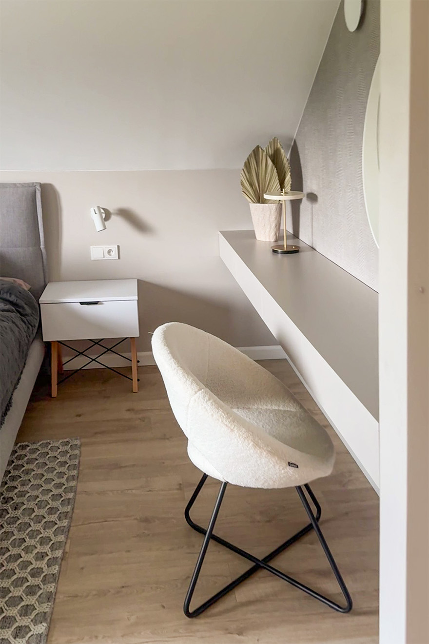 Cremefarbener Polsterstuhl neben dem Schminktisch in einem minimalistischen Schlafzimmer