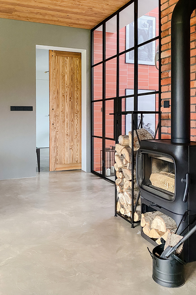 Czarny, metalowy kominek koza w salonie urządzonym w stylu industrialnym.