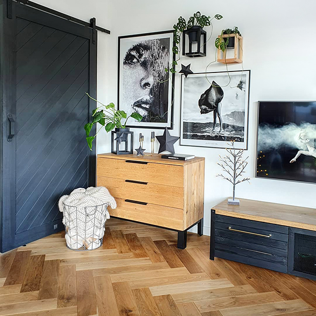 Collage mit Grafiken an der Wand, schwarzen Schiebetüren, Holzschrank mit Metallbeinen