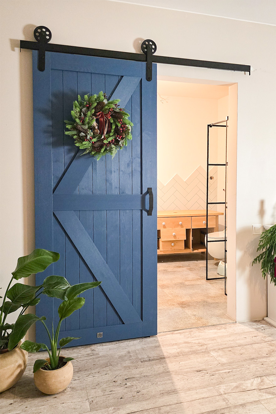 niebieskie drzwi drzwi przesuwne w stylu 'barn door" prowadzące do łazienki