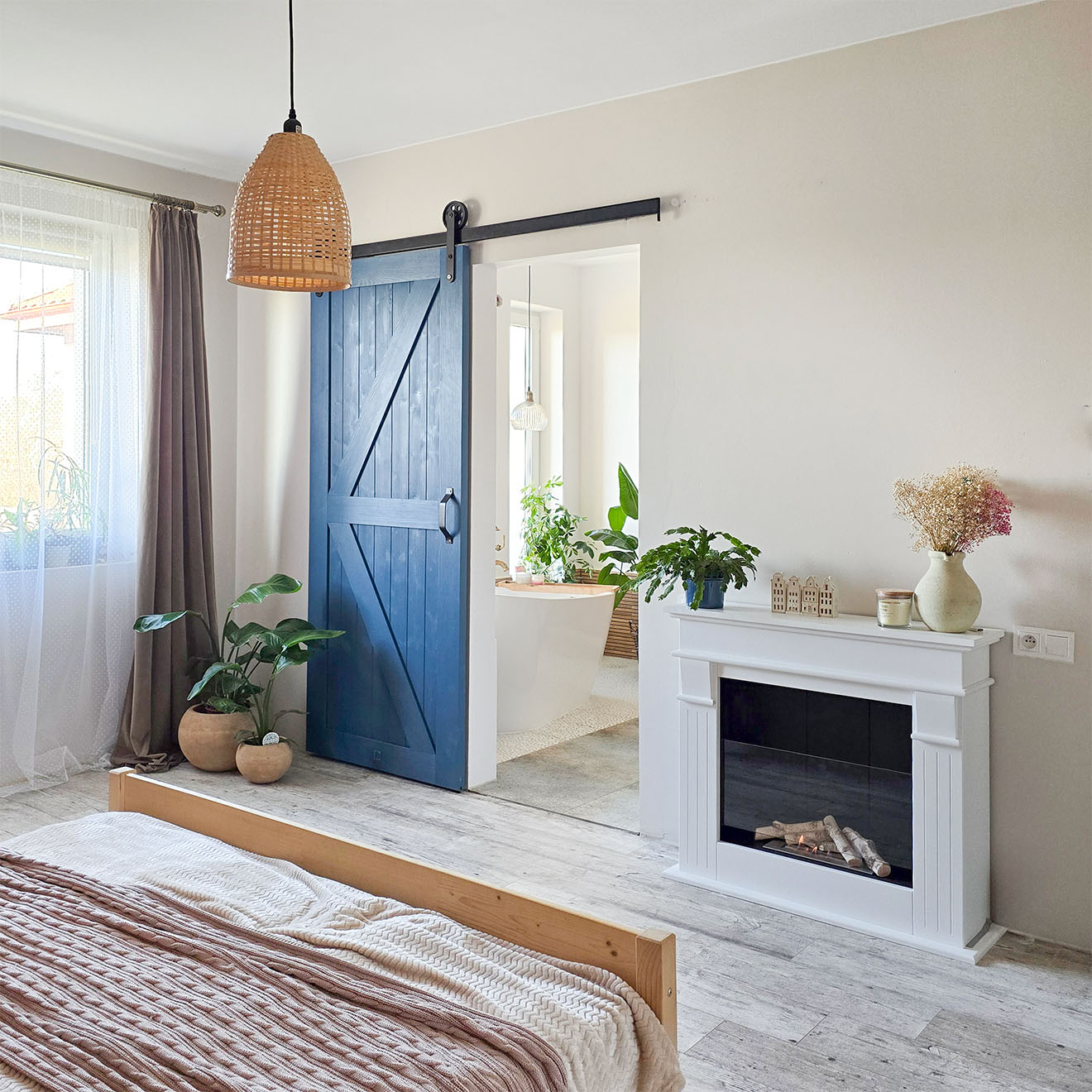 aranżacja sypialni z kominkiem i niebieskimi drzwiami przesuwnymi prowadzącymi do prywatnej łazienki