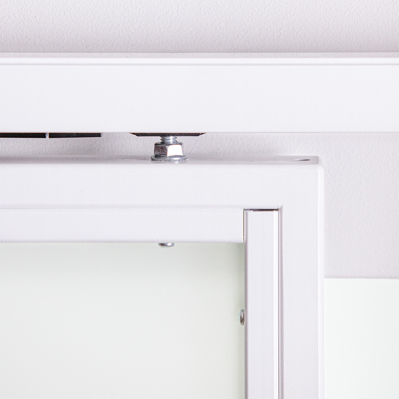 Ujęcie detalu mocowania białych drzwi przesuwnych do białej prowadnicy, z widocznym elementem regulacyjnym i śrubą.
