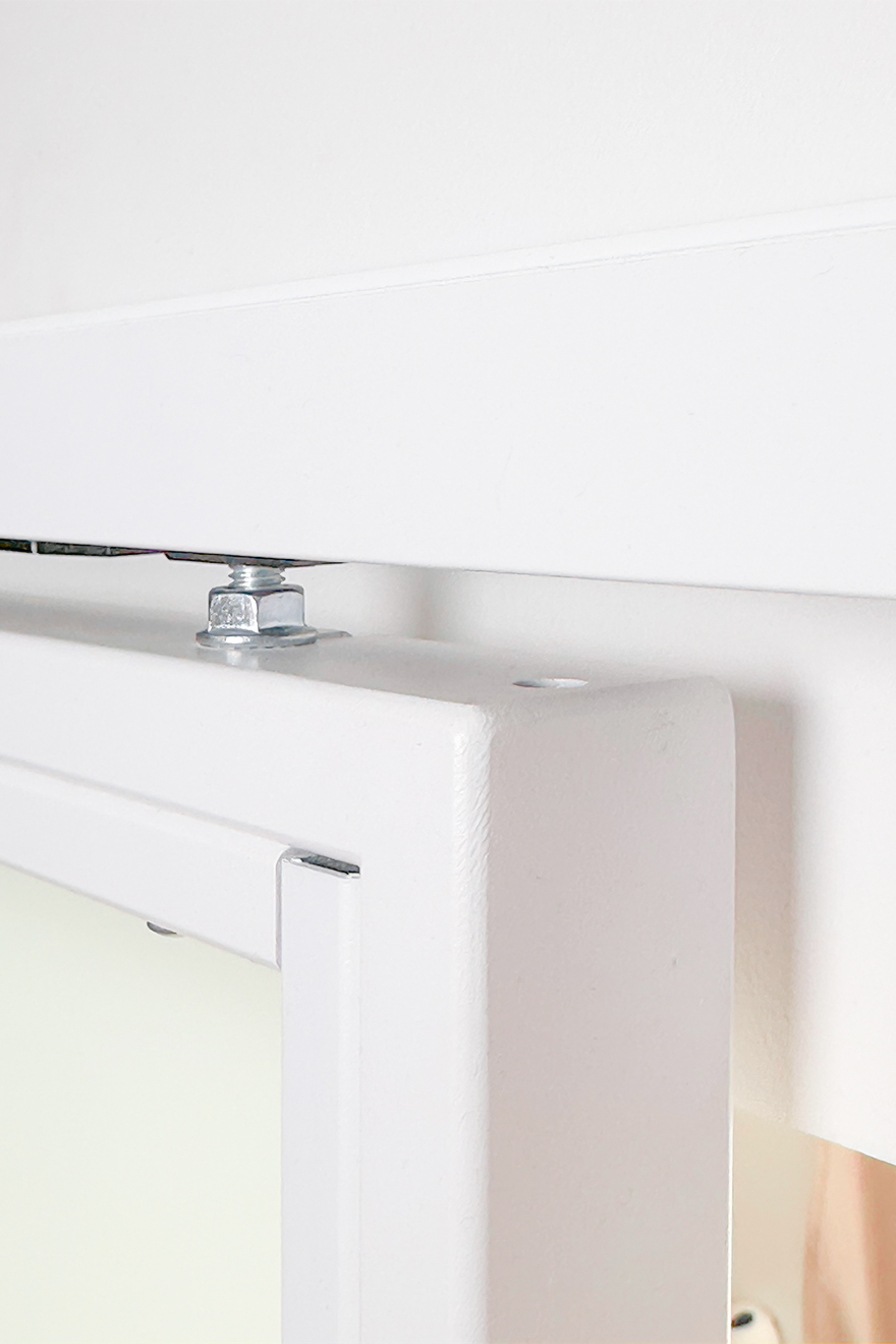 Nahaufnahme des Befestigungsmechanismus der weißen Schiebetüren an der oberen Führungsschiene.