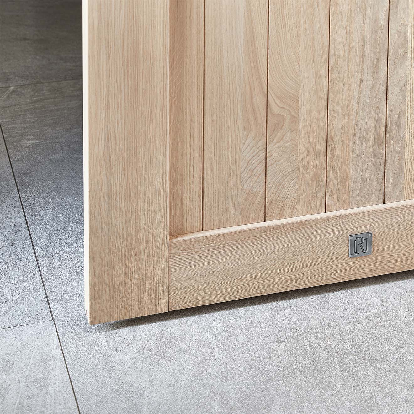 Eine Nahaufnahme der unteren Ecke einer Eichenschiebetür, die die Holzmaserung zeigt. Dieses Foto unterstreicht die hohe handwerkliche Qualität und die natürliche Schönheit der Eiche.