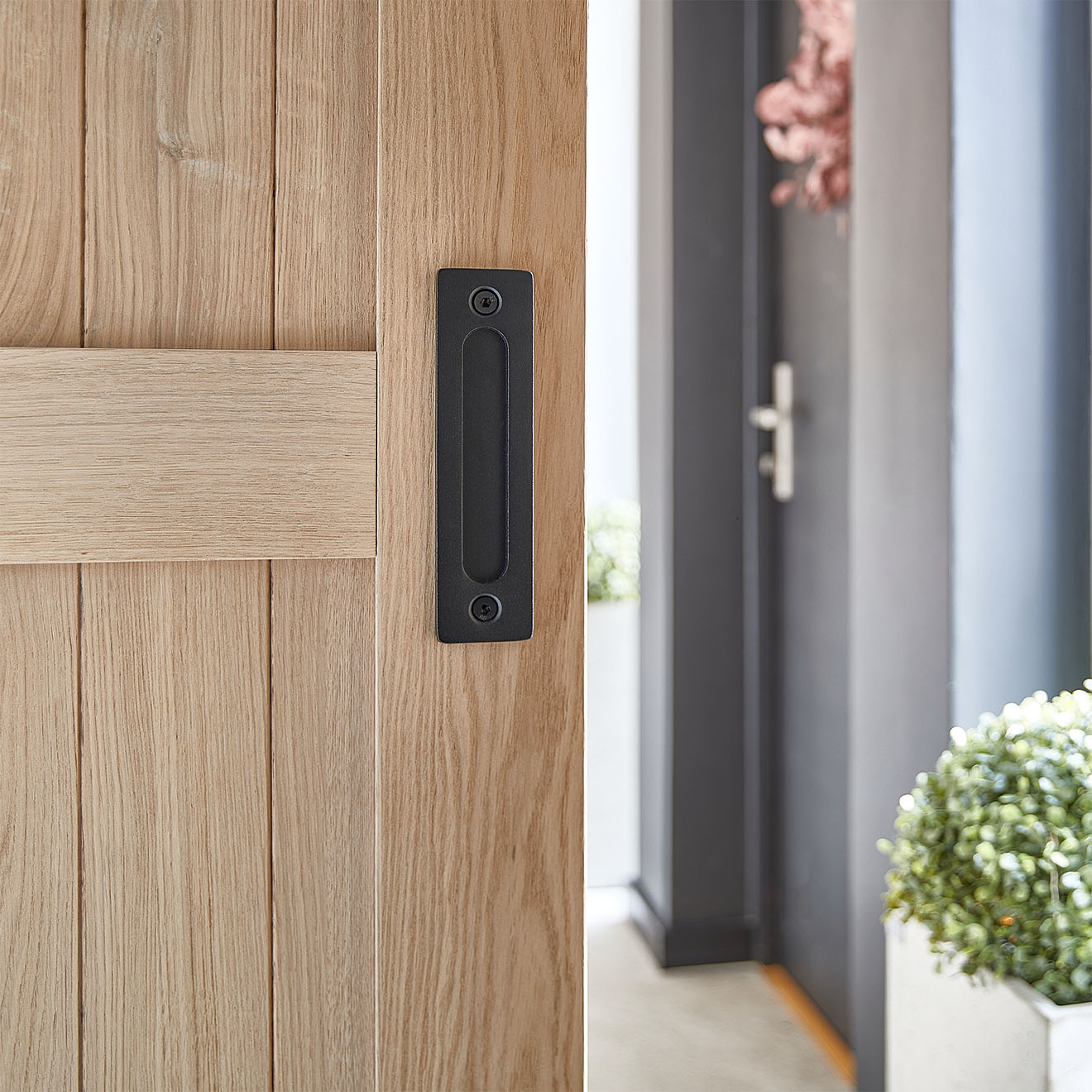 Ein versenkter schwarzer Griff an der Schiebetür aus Eiche. Das Griffdetail spricht Bände über die Liebe zum Detail und das minimalistische Design.