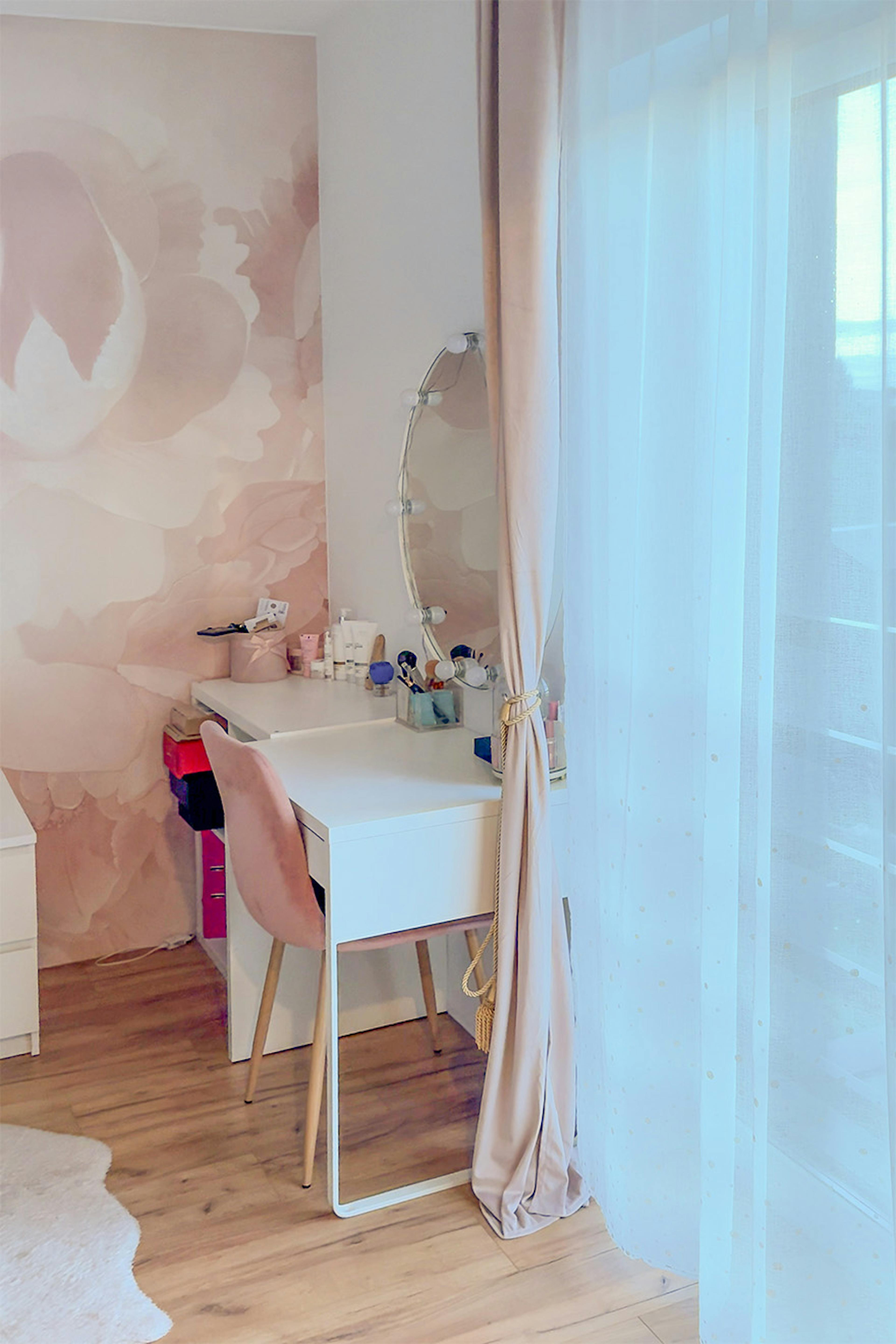 Białe biurko/toaletka i różowe welurowe krzesło; Okrągłe lustro oświetlone w stylu Hollywood.