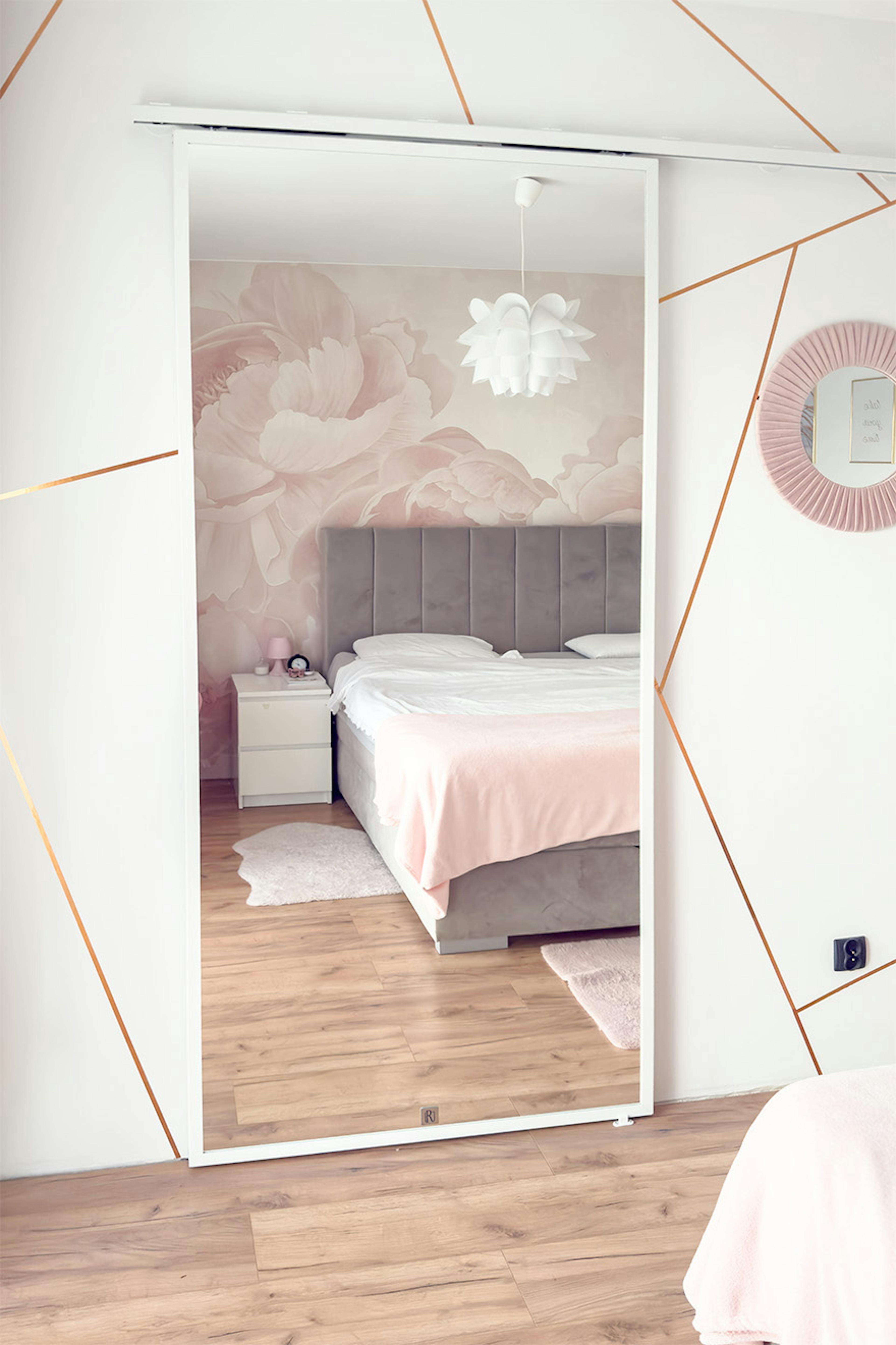 Schiebetüren mit Spiegel für den Ankleidezimmer; Schlafzimmer mit Bett und gestepptem grauen Kopfteil; Spiegel, der den Raum optisch vergrößert.