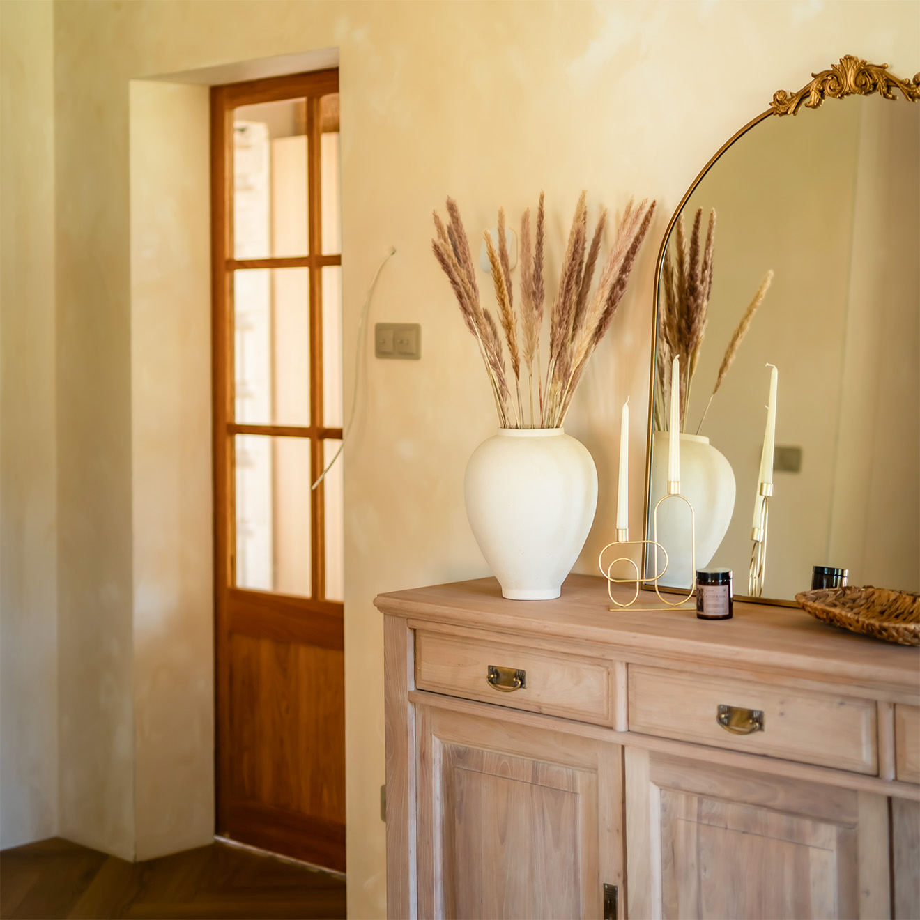 Holzkonsolen mit Spiegel und Vase im Flur, im Hintergrund rustikale Eichenholztüren mit Glasfüllung.