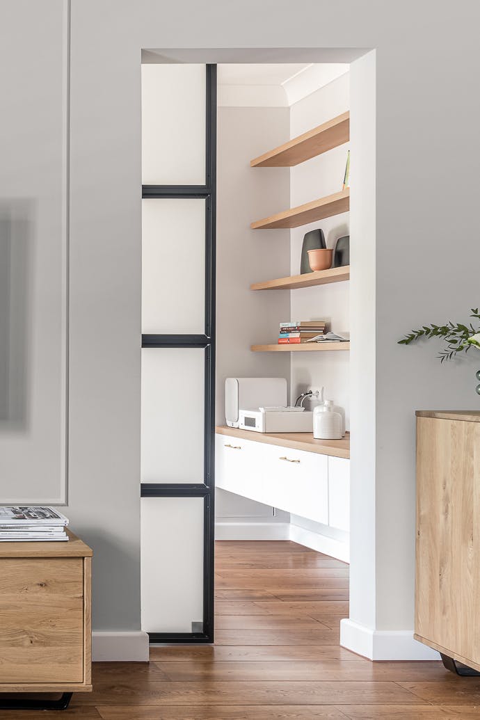 Türöffnung zwischen den Räumen, Schiebetüren aus Metall und Glas, mit Milchglas gefüllter Metallrahmen, Holzboden im Wohnzimmer, helle Holzmöbel, helle Farben im Innenraum