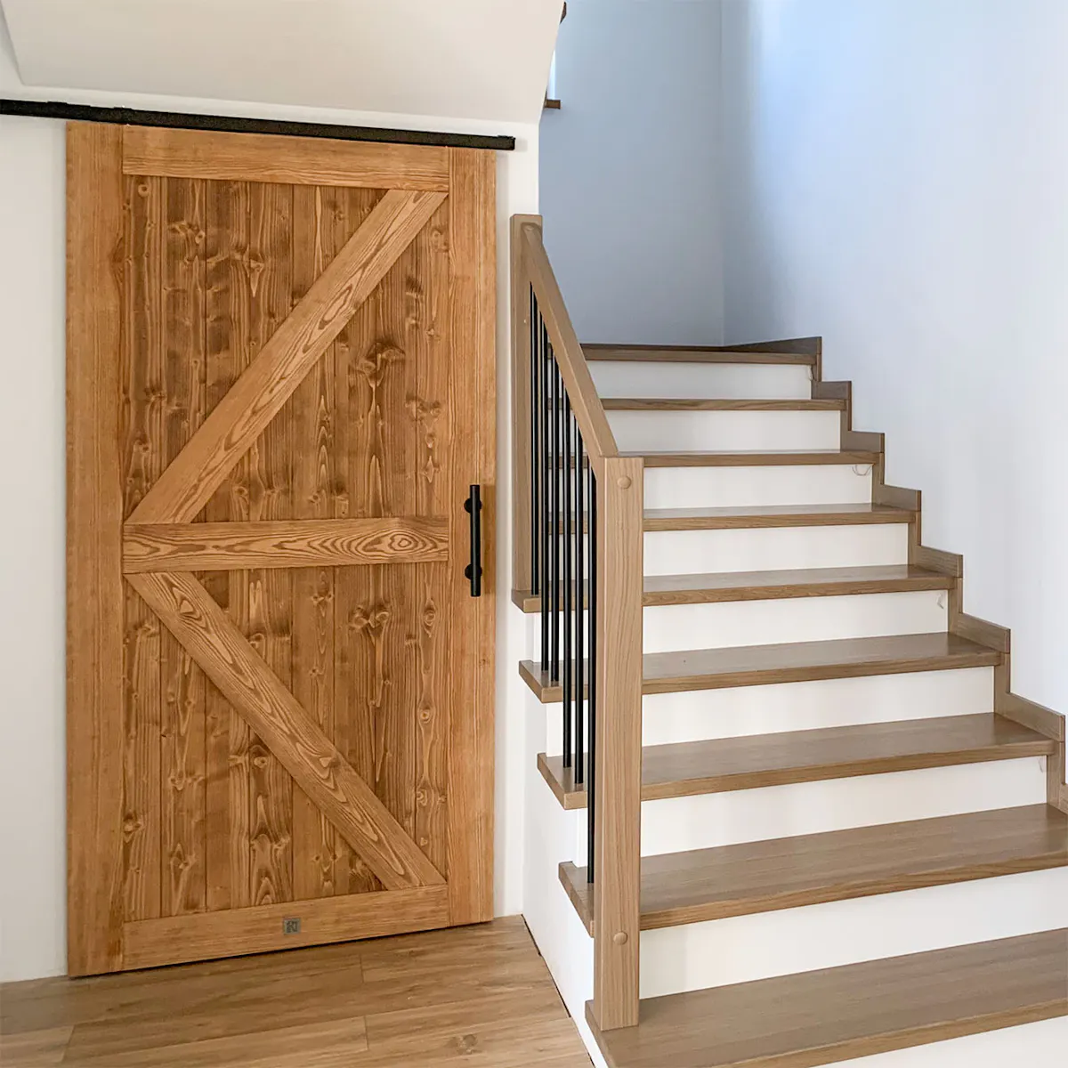 Drewniane drzwi przesuwne typu barn door zamontowane pod skosem przy schodach na systemie TOP WALL.