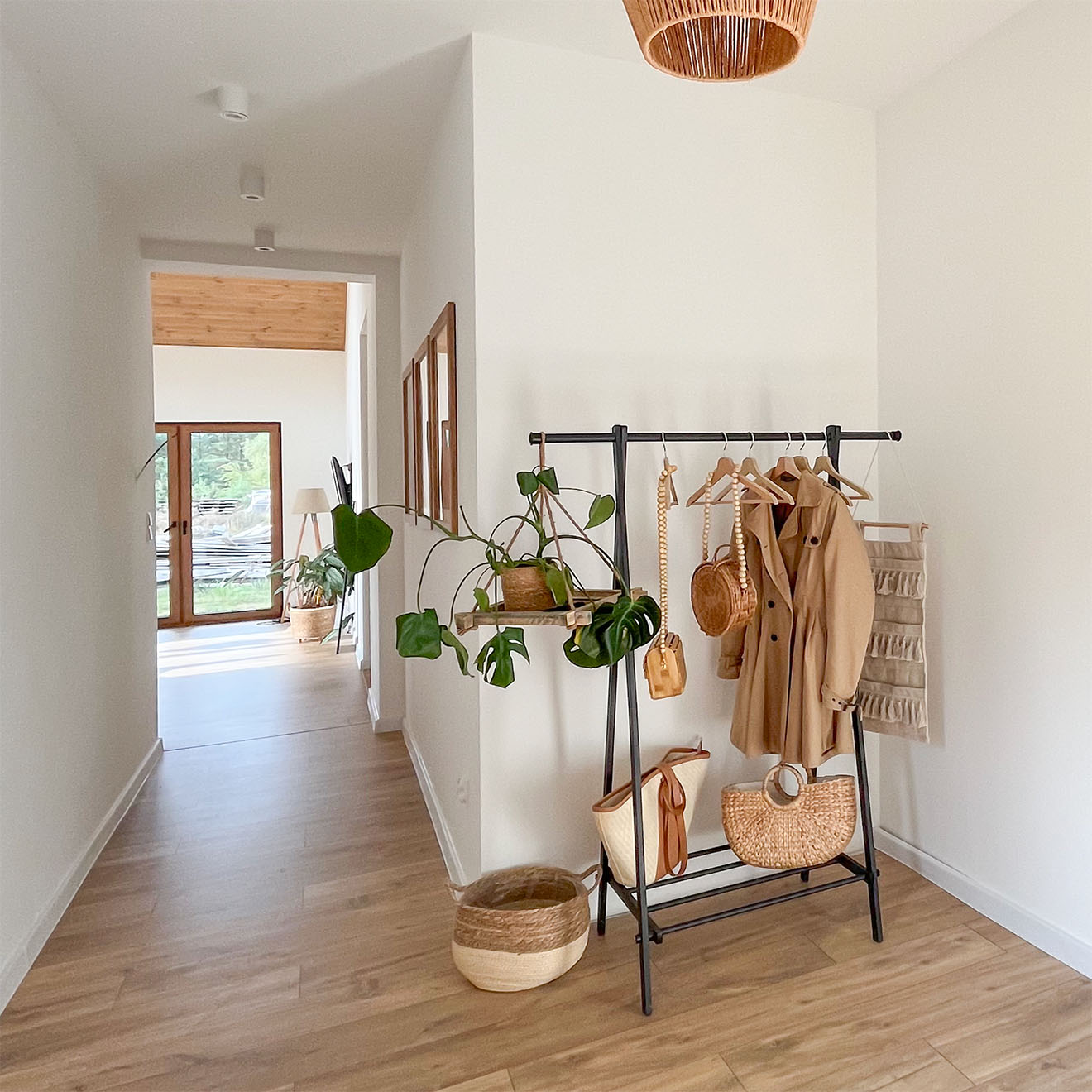 metalowy stojak z wieszakami na ubrania w przedpokoju domu jednorodzinnego