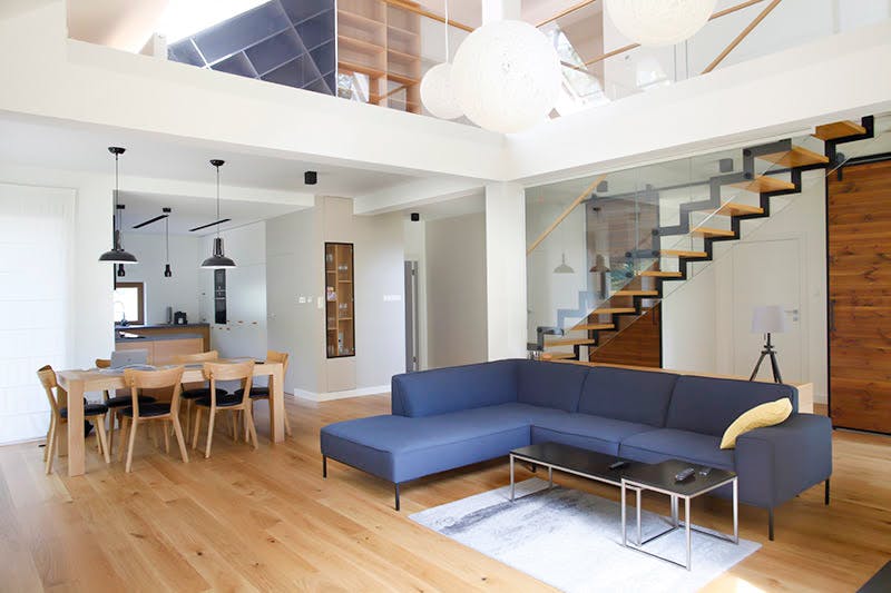 duża niebieska sofa w salonie na otwartym planie w nowoczesnym domu