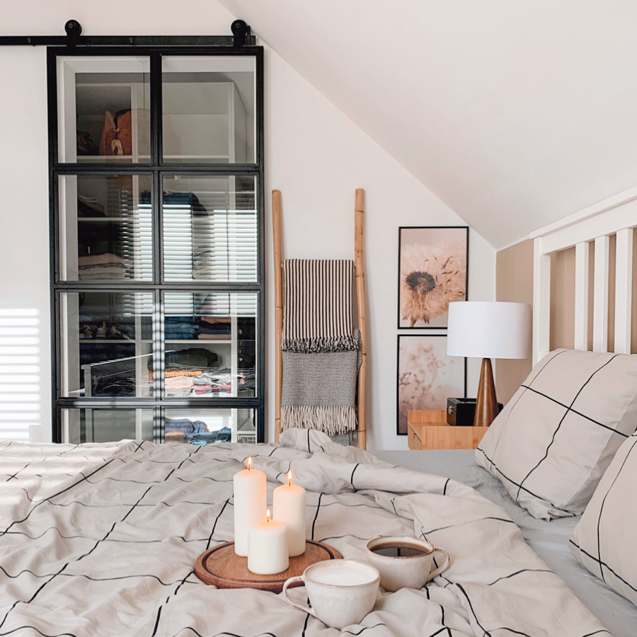 sypialnia na poddaszu z małą garderobą ukrytą za szklanymi drzwiami przesuwnymi