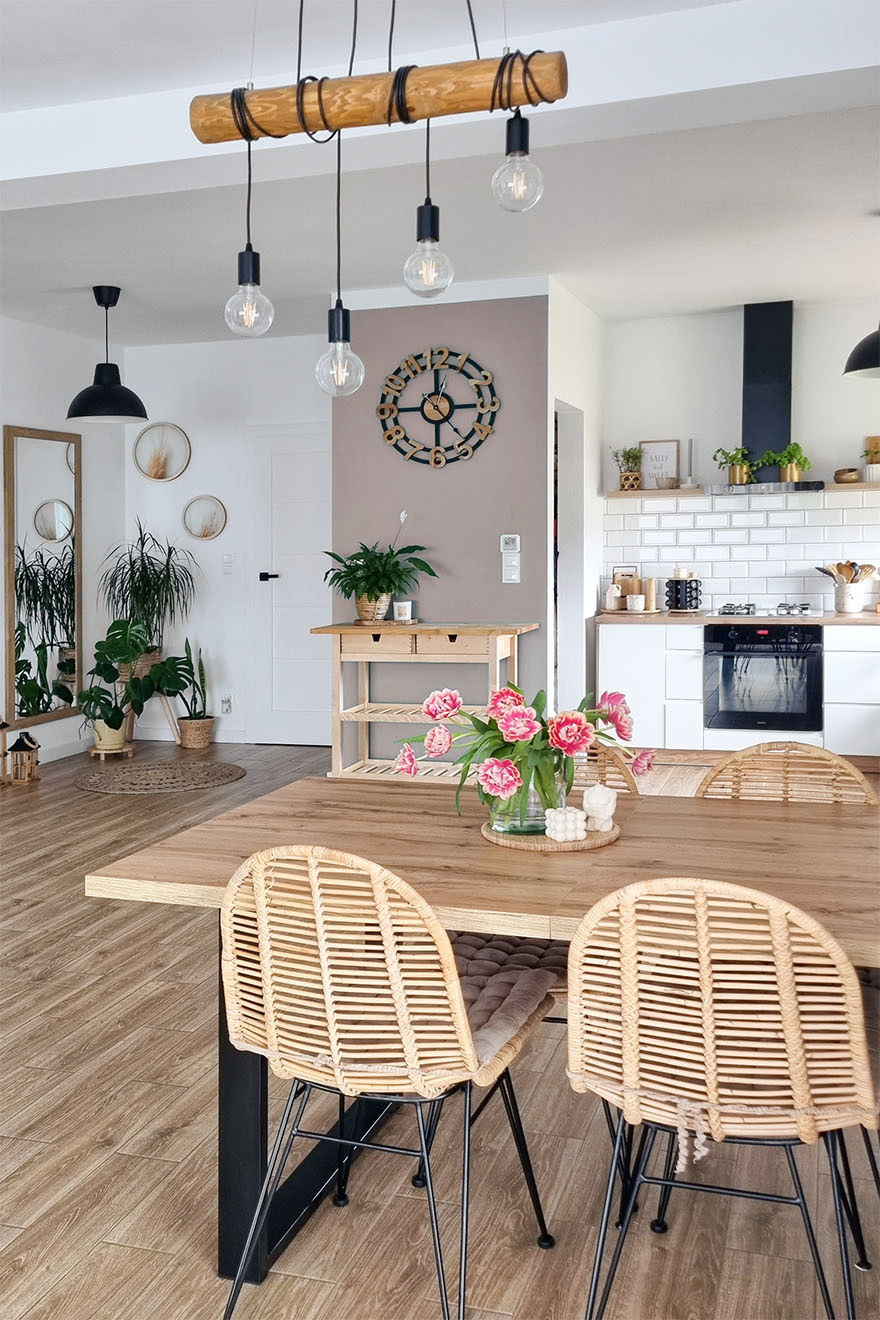 Durchbrochene Stühle an einem Tisch mit Holzplatte in einem offenen Esszimmer kombiniert mit einer Küche im skandinavischen Stil