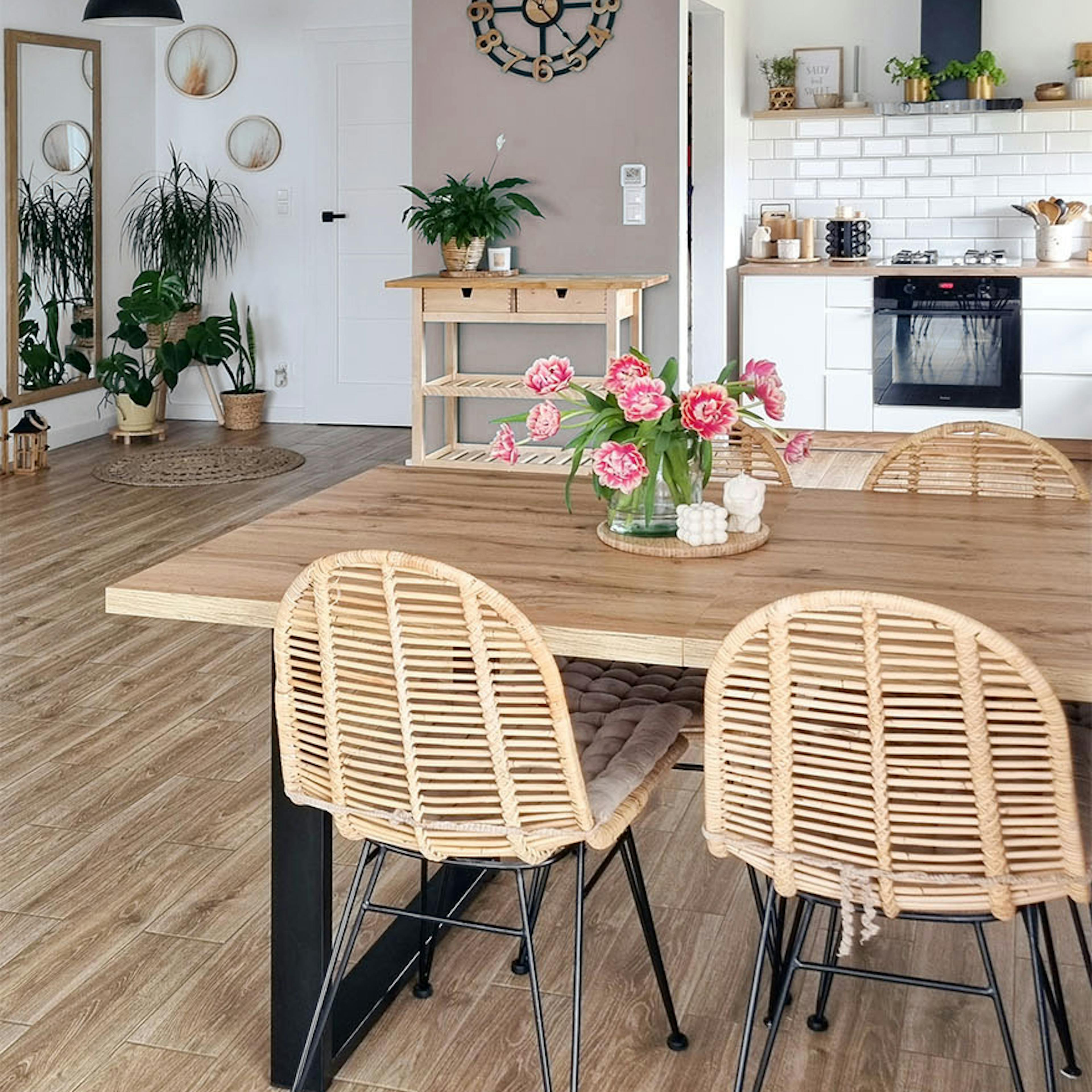 Durchbrochene Stühle an einem Tisch mit Holzplatte in einem offenen Esszimmer kombiniert mit einer Küche im skandinavischen Stil