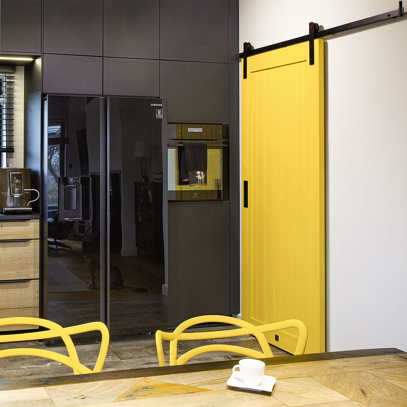 żółte drzwi przesuwne do spiżarni w kuchni z czarnymi szafkami