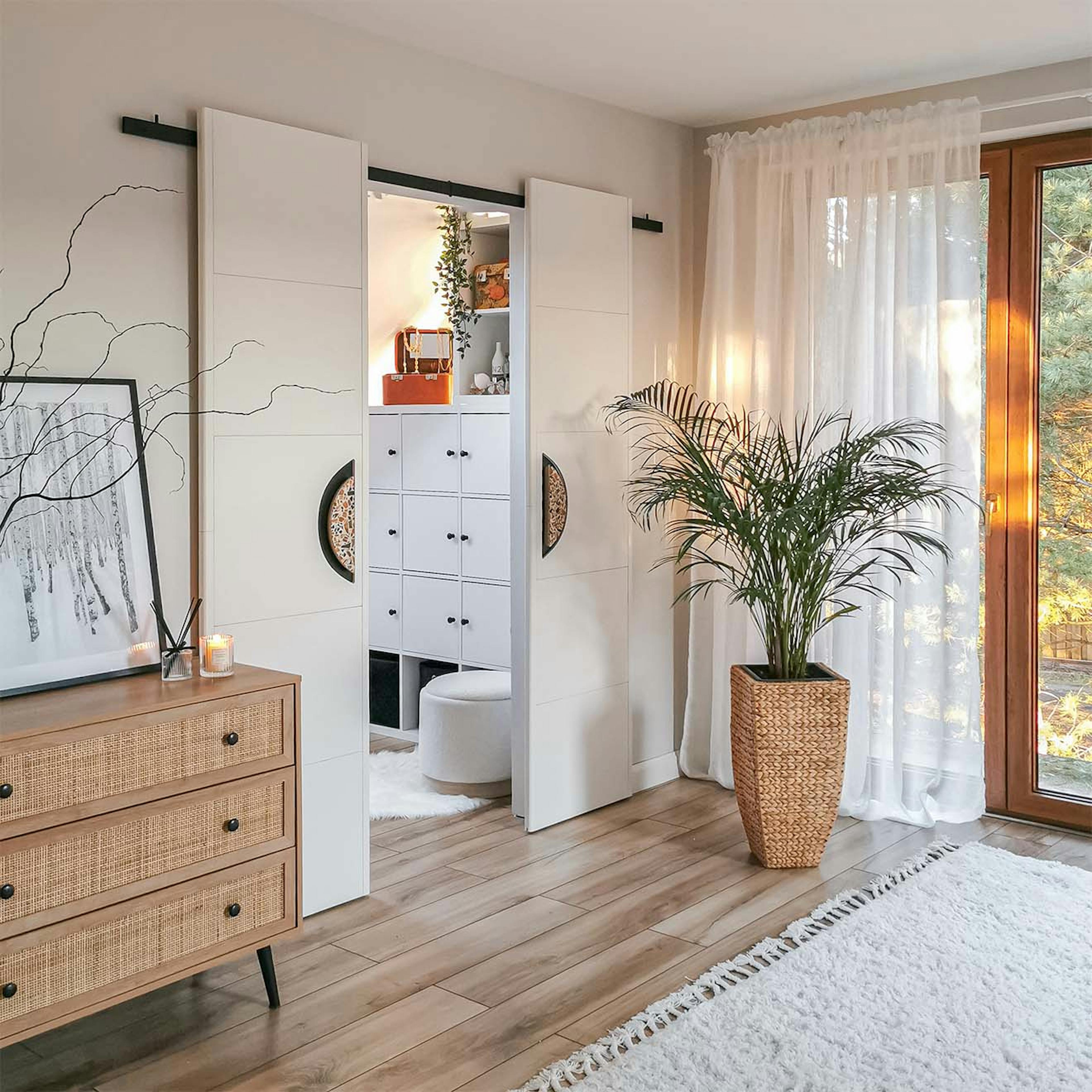 Schlafzimmer mit begehbarem Kleiderschrank hinter weißen Doppelschiebetüren