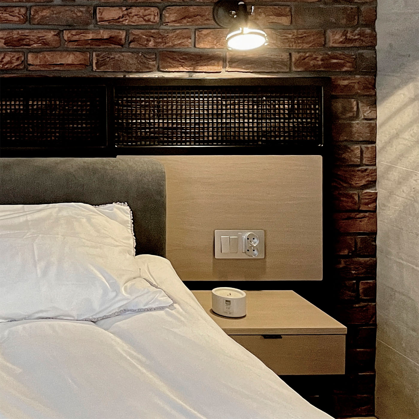 roter Backstein an der Wand in einem industriellen Schlafzimmer, Loft-Nachttisch, dekorative Metallplatte hinter dem Bett in einem industriellen Schlafzimmer