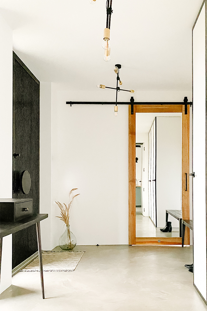 Industrialna lampa, czarny minimalistyczny stolik i drzwi przesuwne z lustrem w wiatrołapie