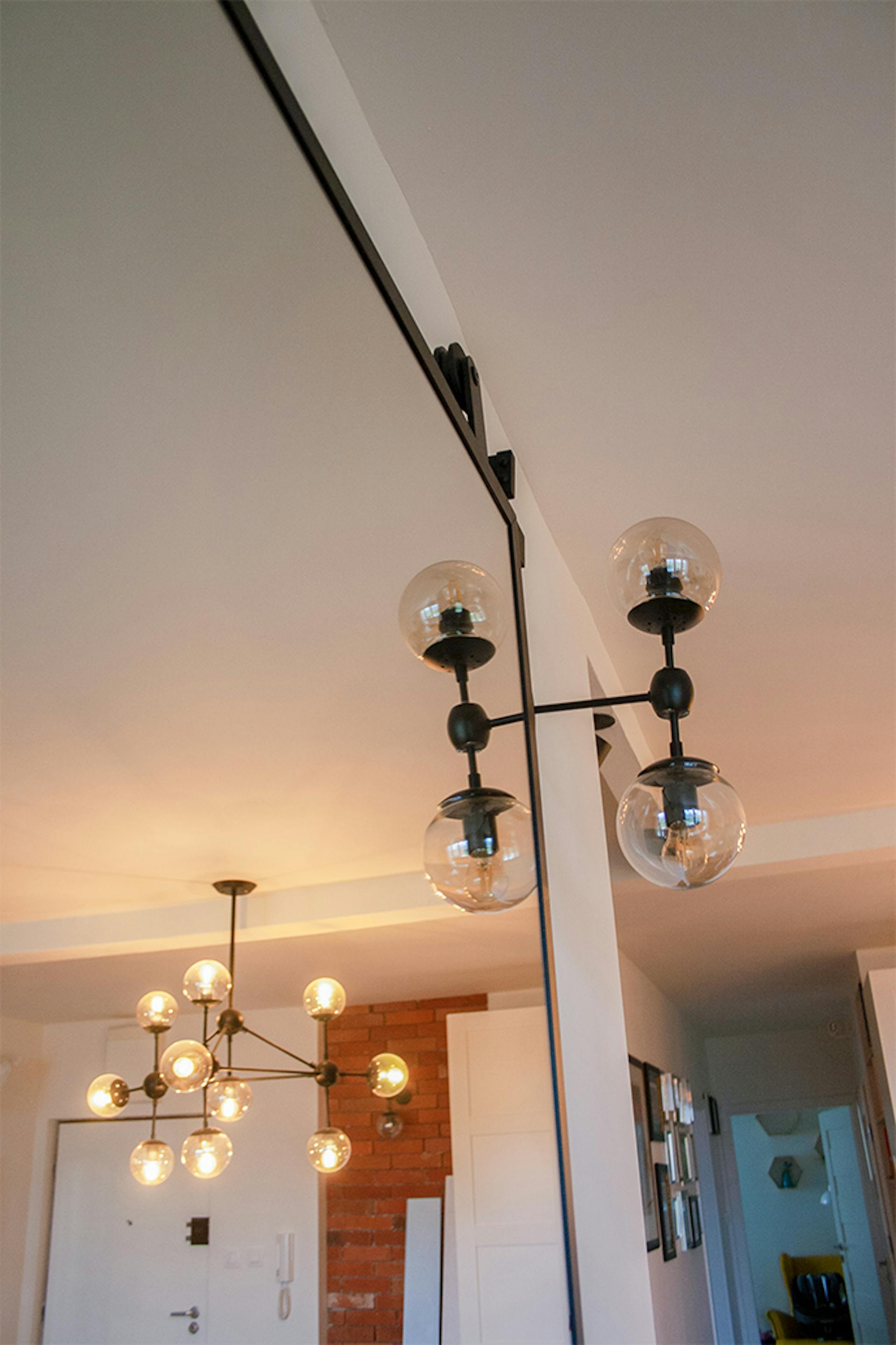 Schiebetür mit Spiegel, Tür mit Spiegel in einem Metallrahmen, Schiebetür in einem modernen Innenraum, hängende Glaslampen aus Metall