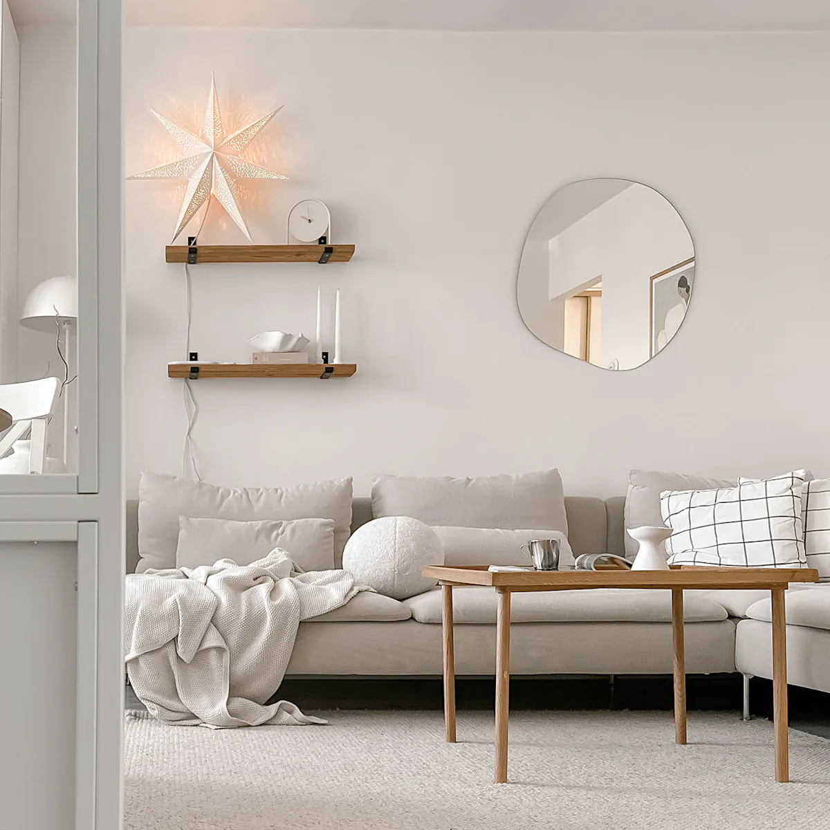 sofa w neutralnym odcieniu, drewniany stolik kawowy w jasnym salonie w bloku