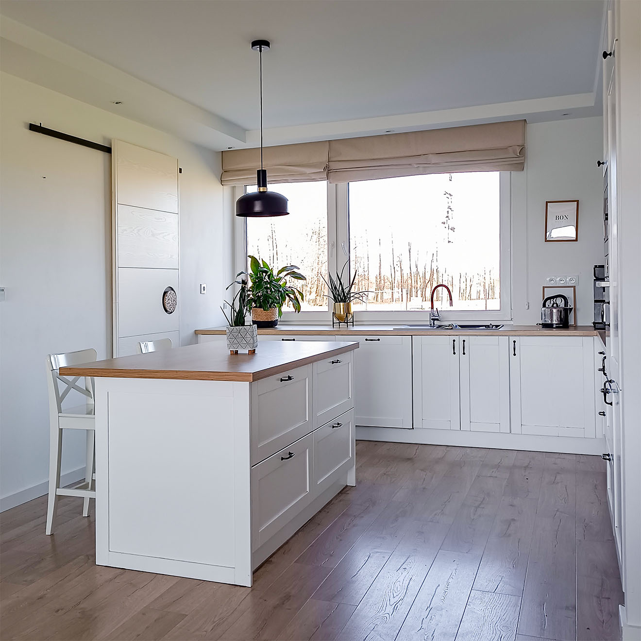 duża wyspa w białej kuchni ze spiżarnią