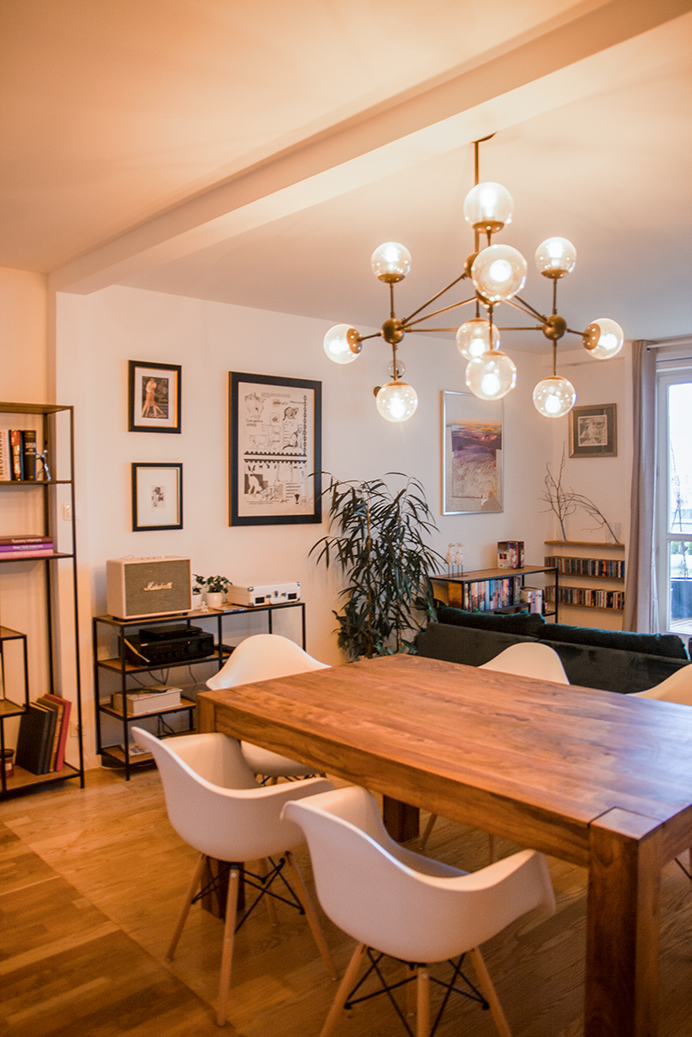 dekorativer Kronleuchter über einem Holztisch in einem eklektischen Wohnzimmer