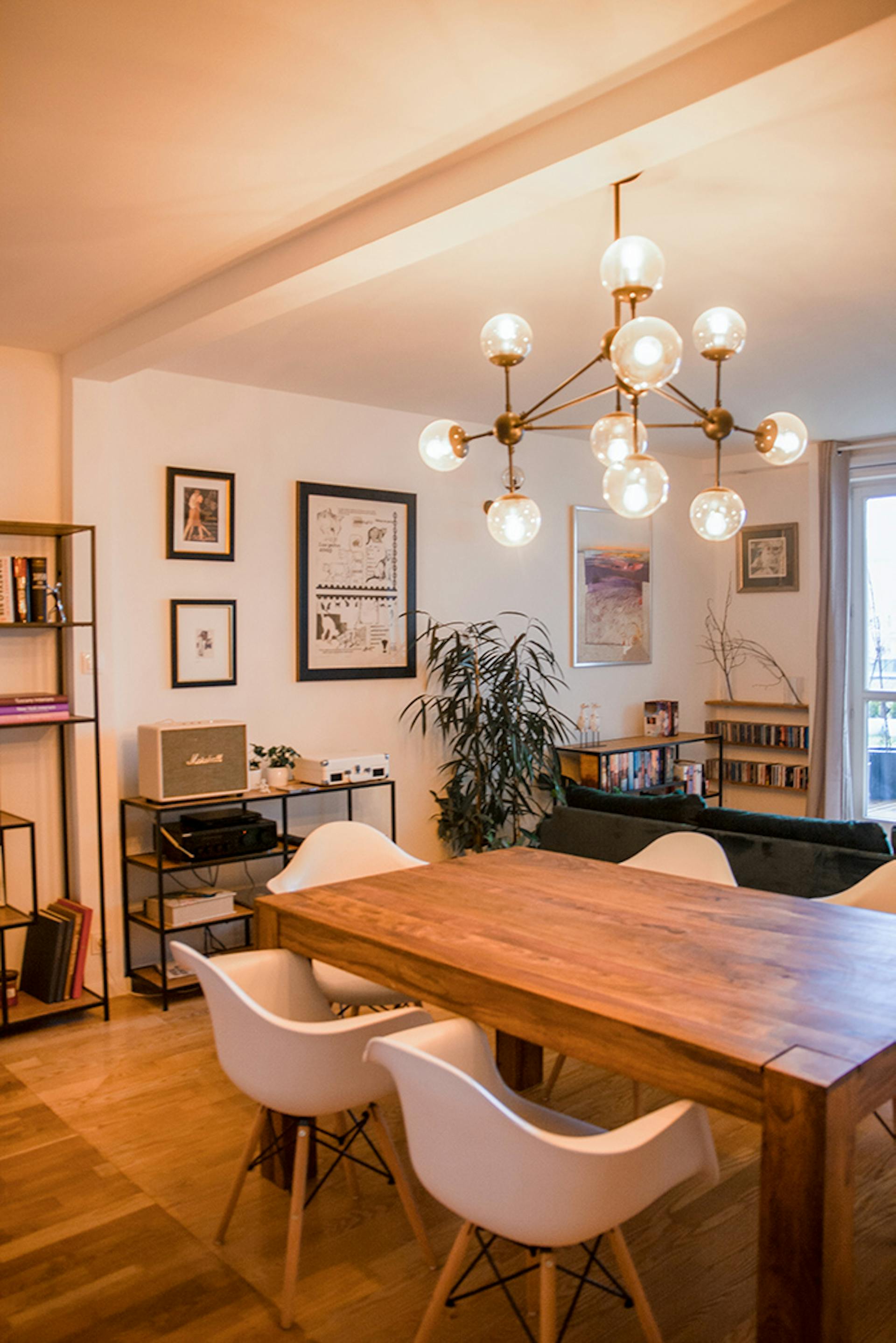 dekorativer Kronleuchter über einem Holztisch in einem eklektischen Wohnzimmer