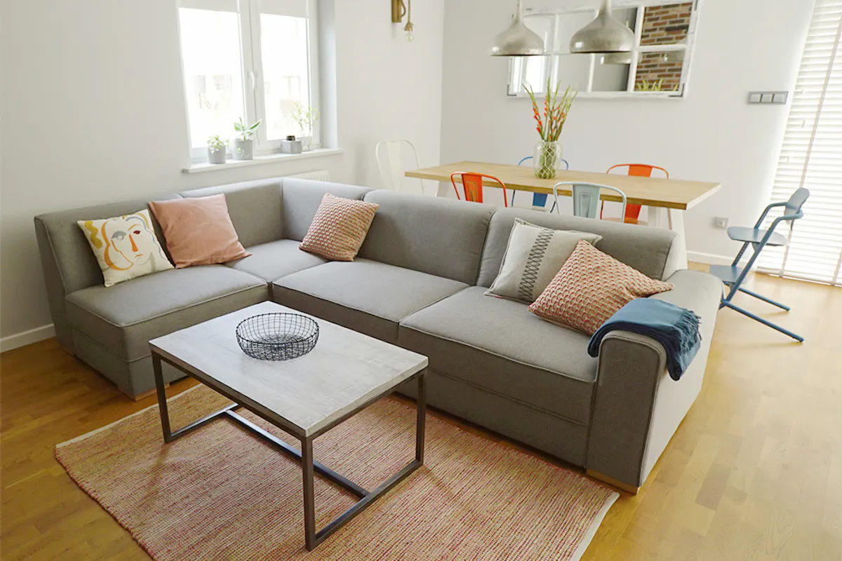 szara sofa w salonie, kącik jadalny w salonie, kolorowe krzesła do jadalni