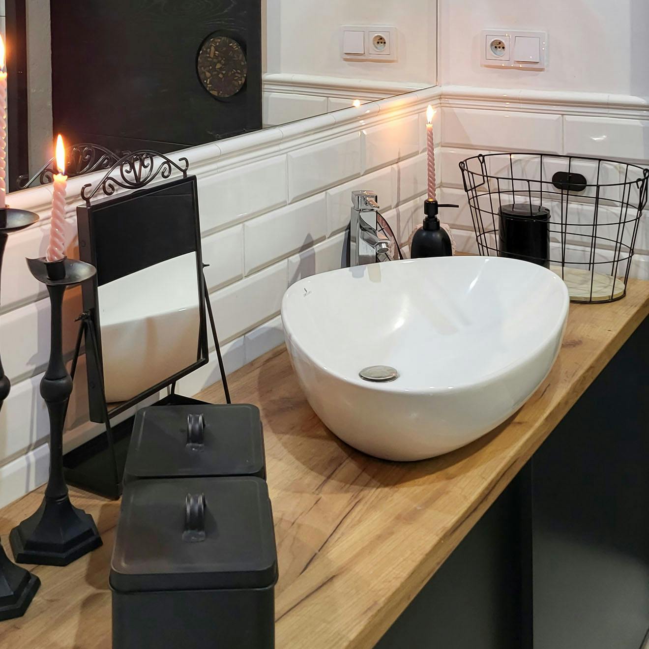 schwarze Accessoires und ein weißes Waschbecken auf einer Holzablage im Badezimmer