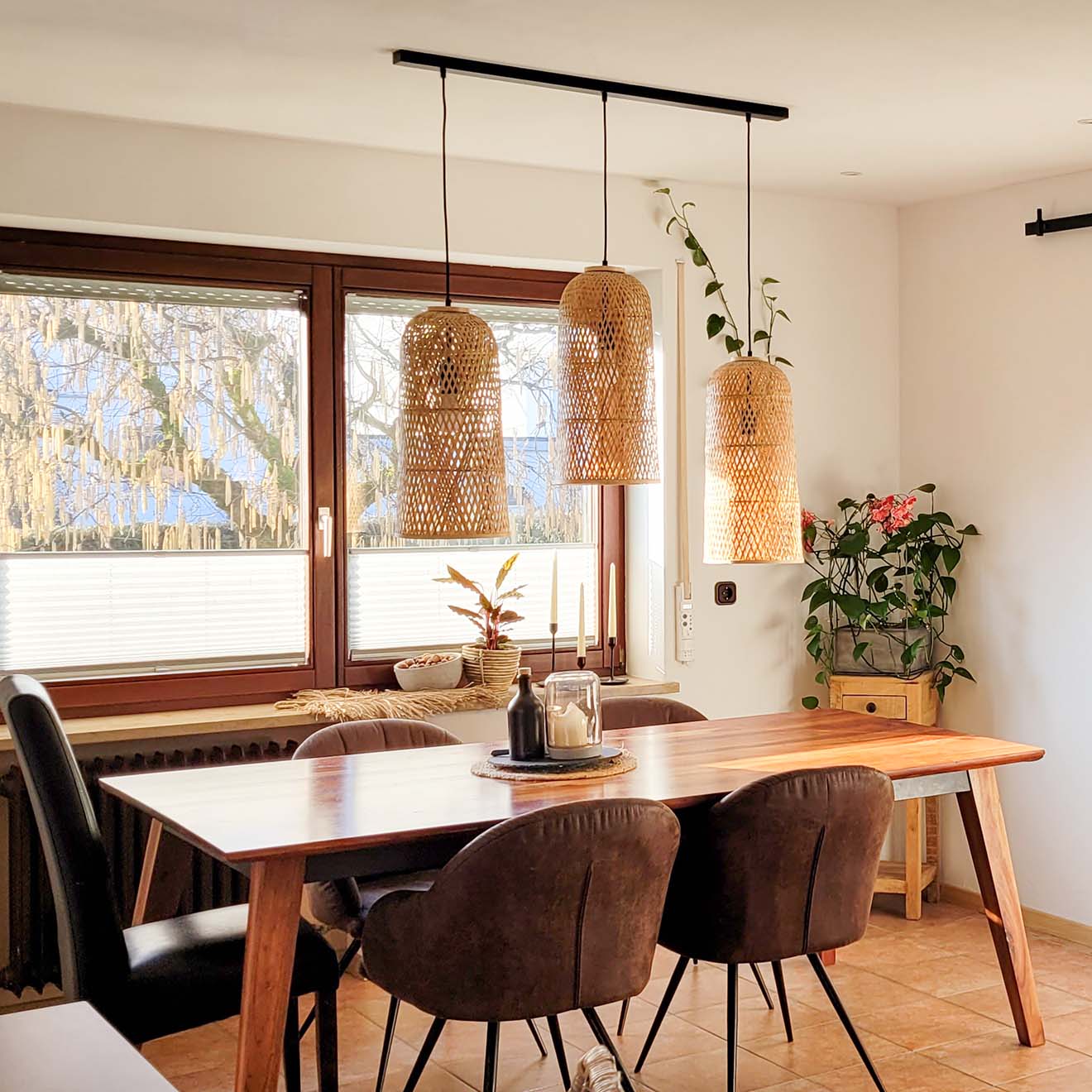 Rattanlampen hängen über einem Holztisch am Fenster