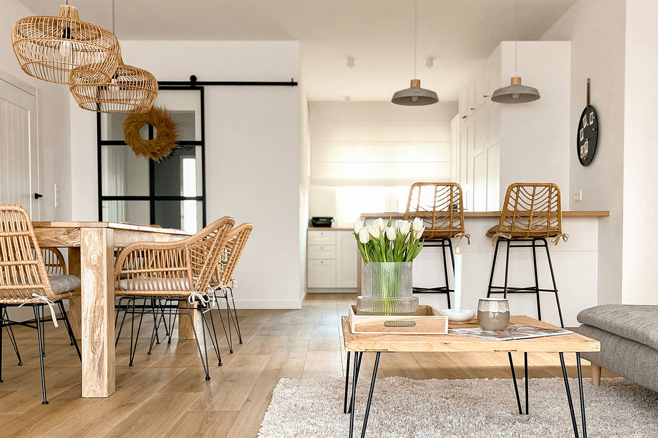 Wohnzimmer mit weißen Wänden und Naturholz-, Rattan- und Korbmöbeln