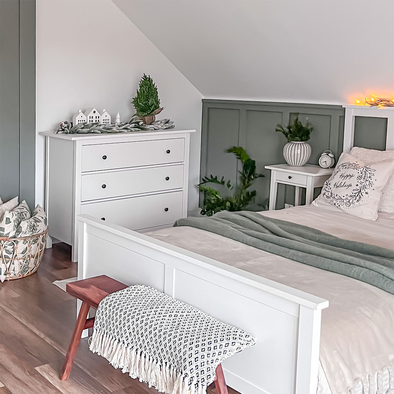 ein weißes Bett und eine weiße Kommode unter einer schrägen Decke im Schlafzimmer