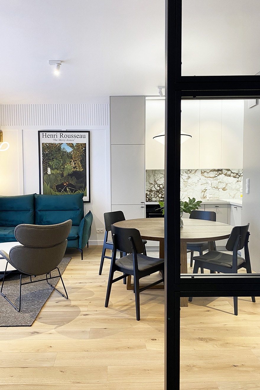 runder Esstisch mit schwarzen Stühlen, helle Küchenzeile, Wohnzimmer mit Küchen-Essbereich