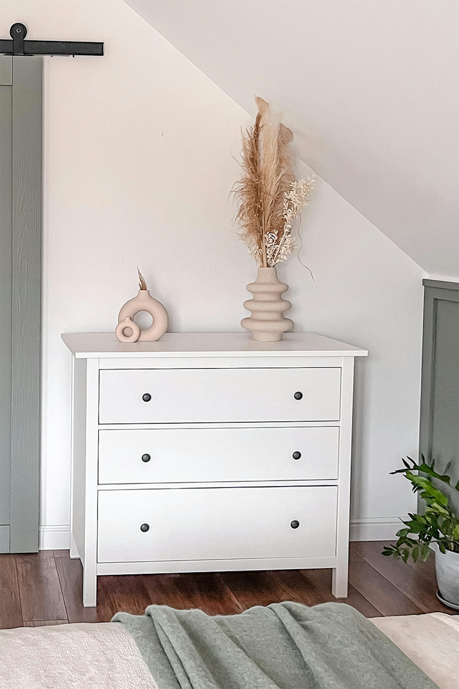 Eine weiße Kommode im skandinavischen Stil steht unter einer schrägen Decke