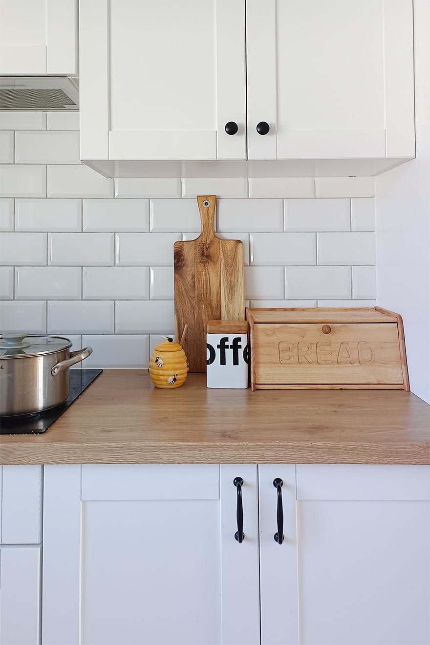 białe meble, białe płytki, drewniany blat w nowoczesnej kuchni