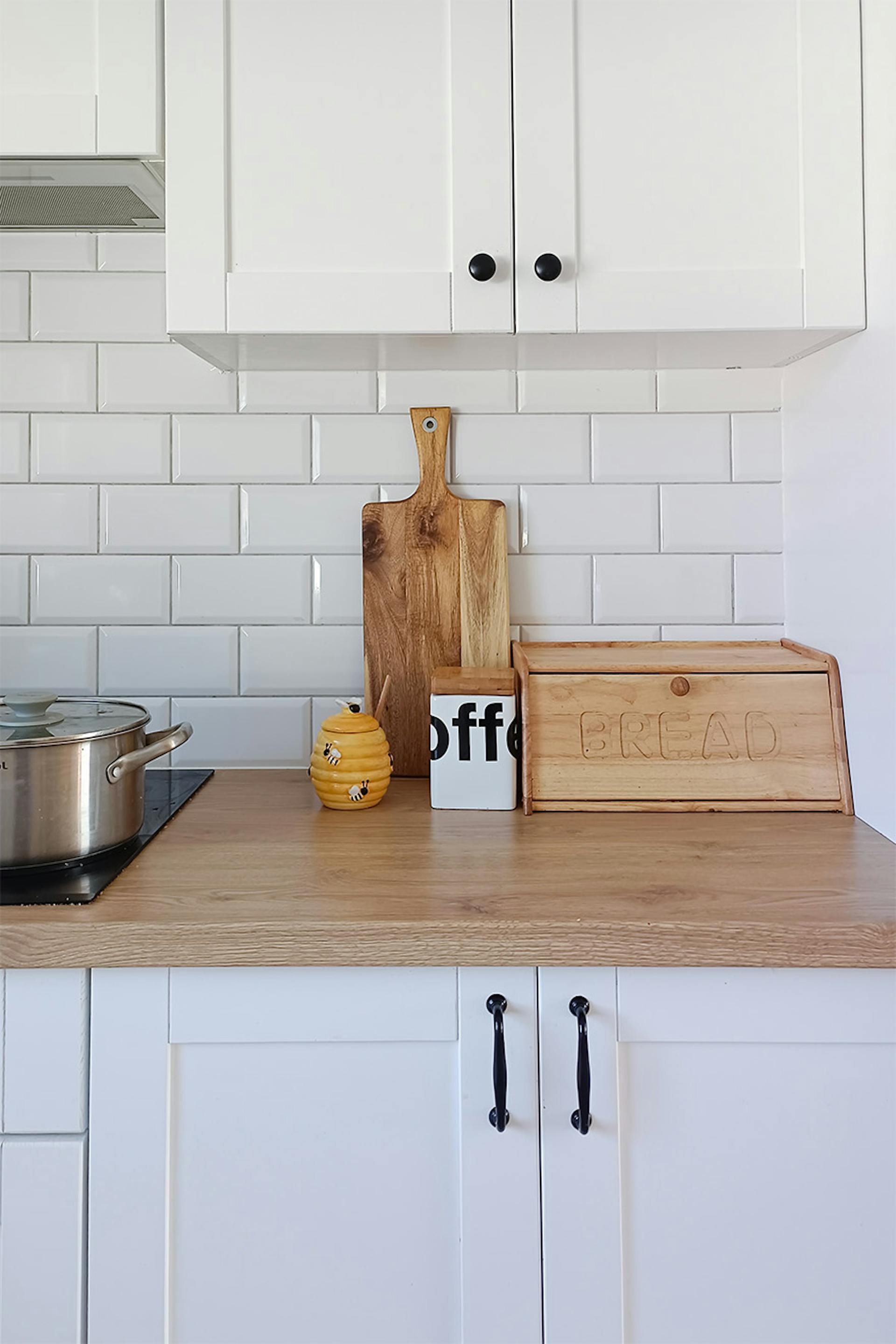 białe meble, białe płytki, drewniany blat w nowoczesnej kuchni