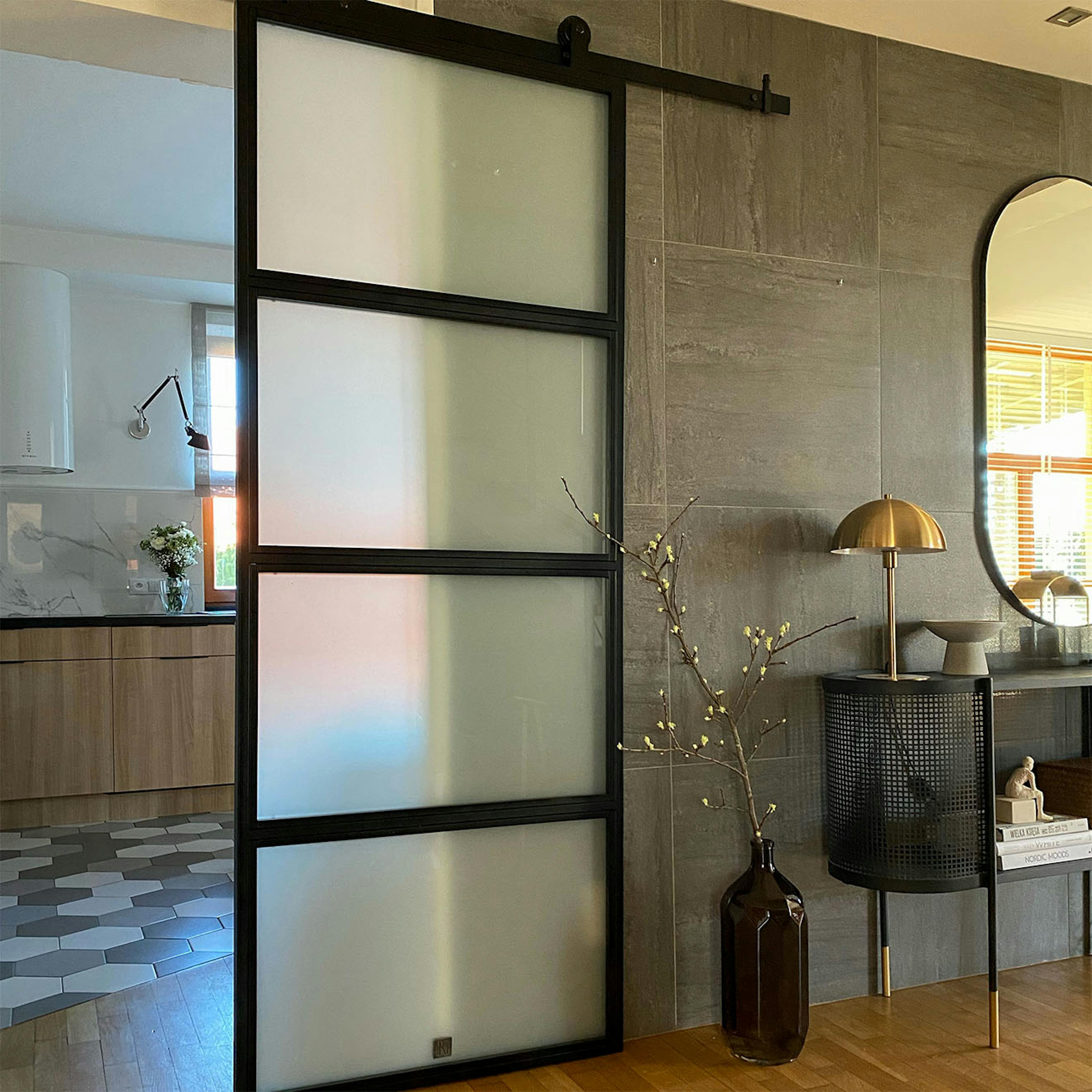 Loft Türen mit glas, Schiebetür zur Küche, Metalltür mit Glas im Durchgang zwischen Küche und Diele, goldene Lampe auf schwarzer Kommode, helle Küche