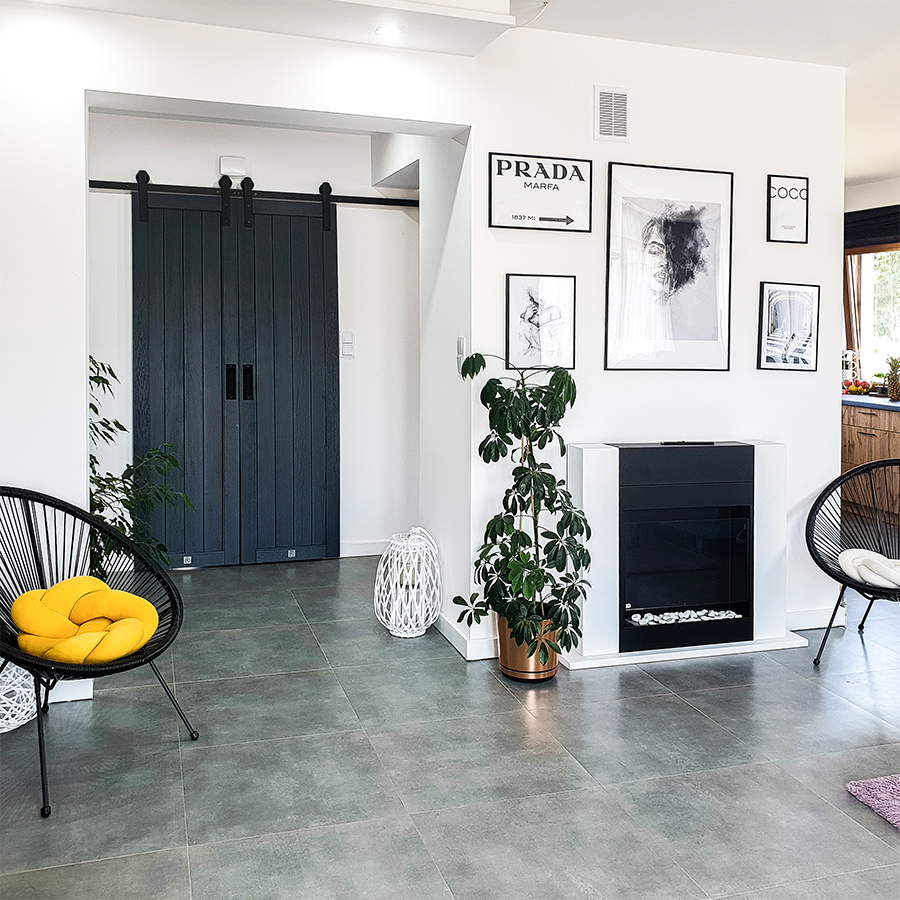 room doors anthracite, anthracite wooden doors, anthracite color doors, double sliding doors, sliding doors in the hall, black accessories in the interior, accessories in anthracite color, photos in a black frame, white and black in a modern home, modern interior, a fireplace in the living room, round openwork armchair