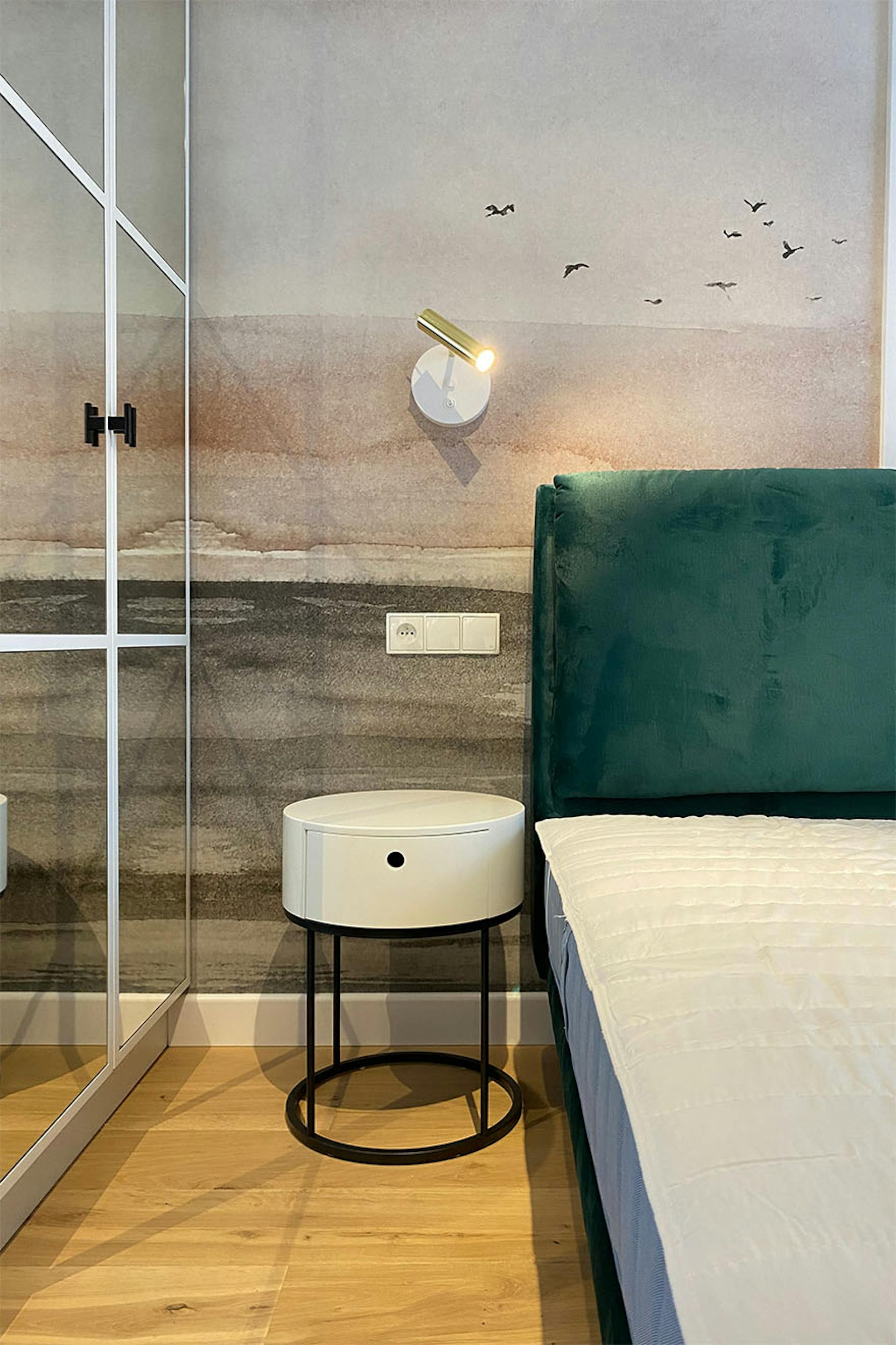 runder weißer Nachttisch, dekorative Tapete im Schlafzimmer, Bett mit gepolstertem Kopfteil, goldene Nachttischlampe