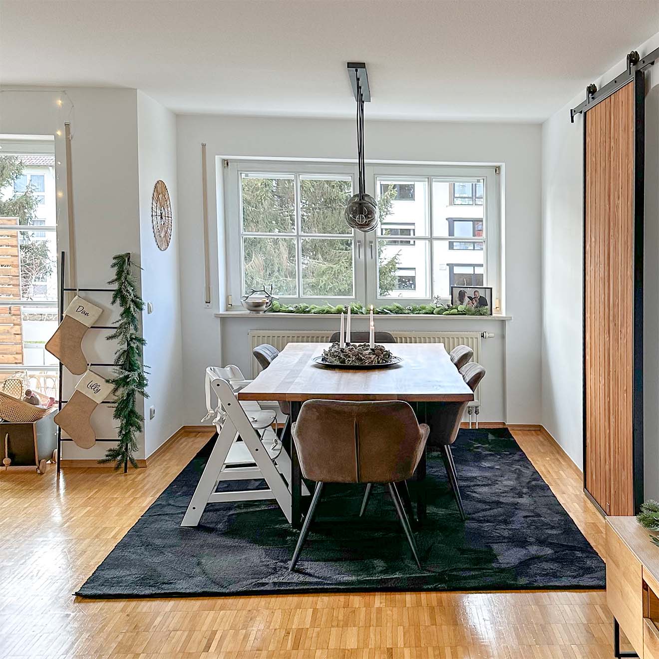 duży stół jadalniany na czarnym dywanie ustawiony obok dużego okna w salonie