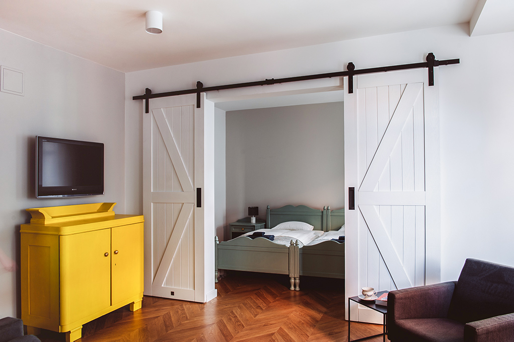 eine gelbe Kommode neben den weißen Doppelschiebetüren