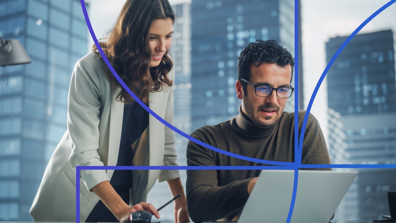 Woman standing behind man sitting and looking at a laptop