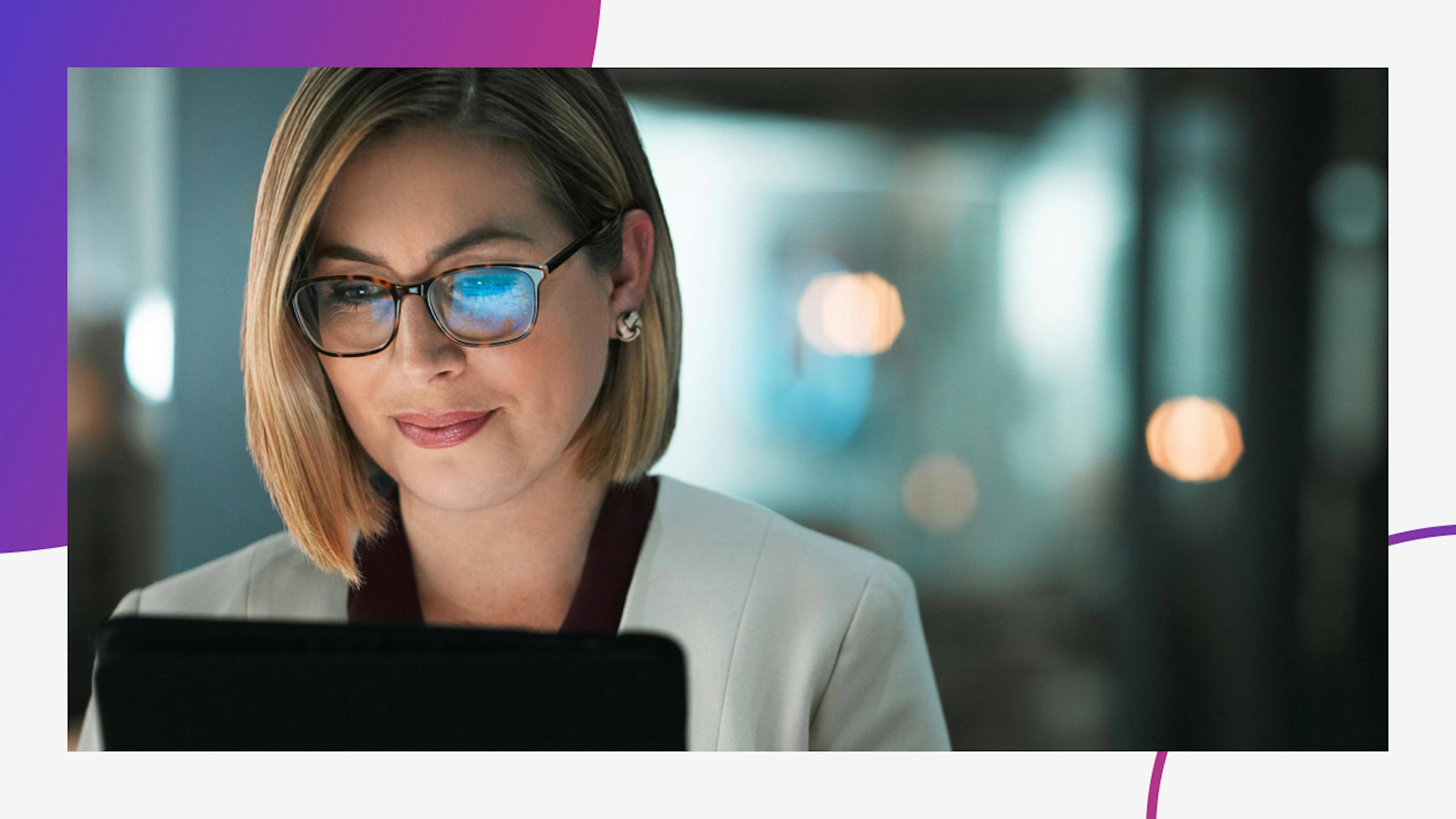 Woman looking at a laptop with the screen reflection on her glasses