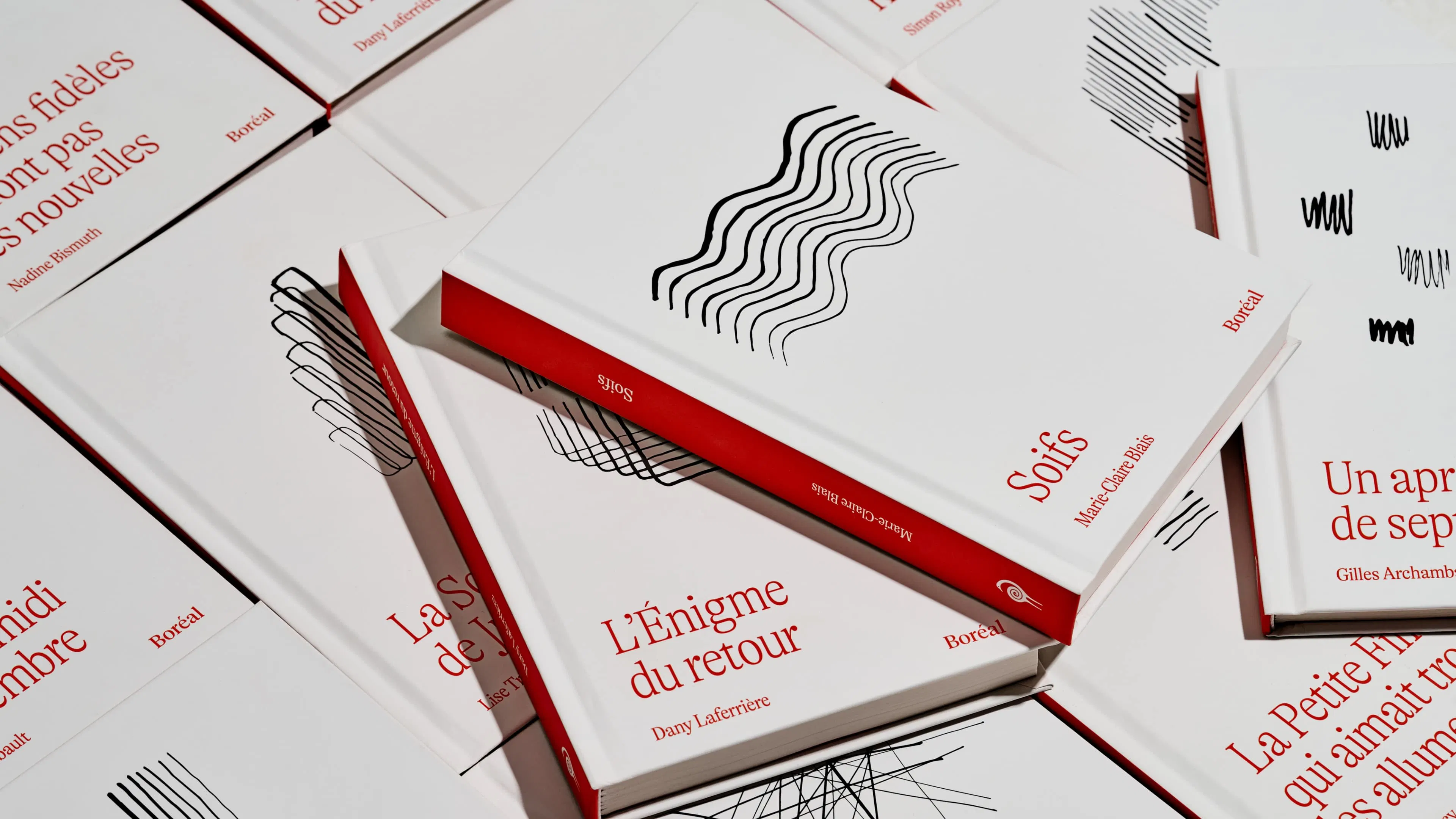 A collection of white books with French titles, red spines and minimalist abstract designs.