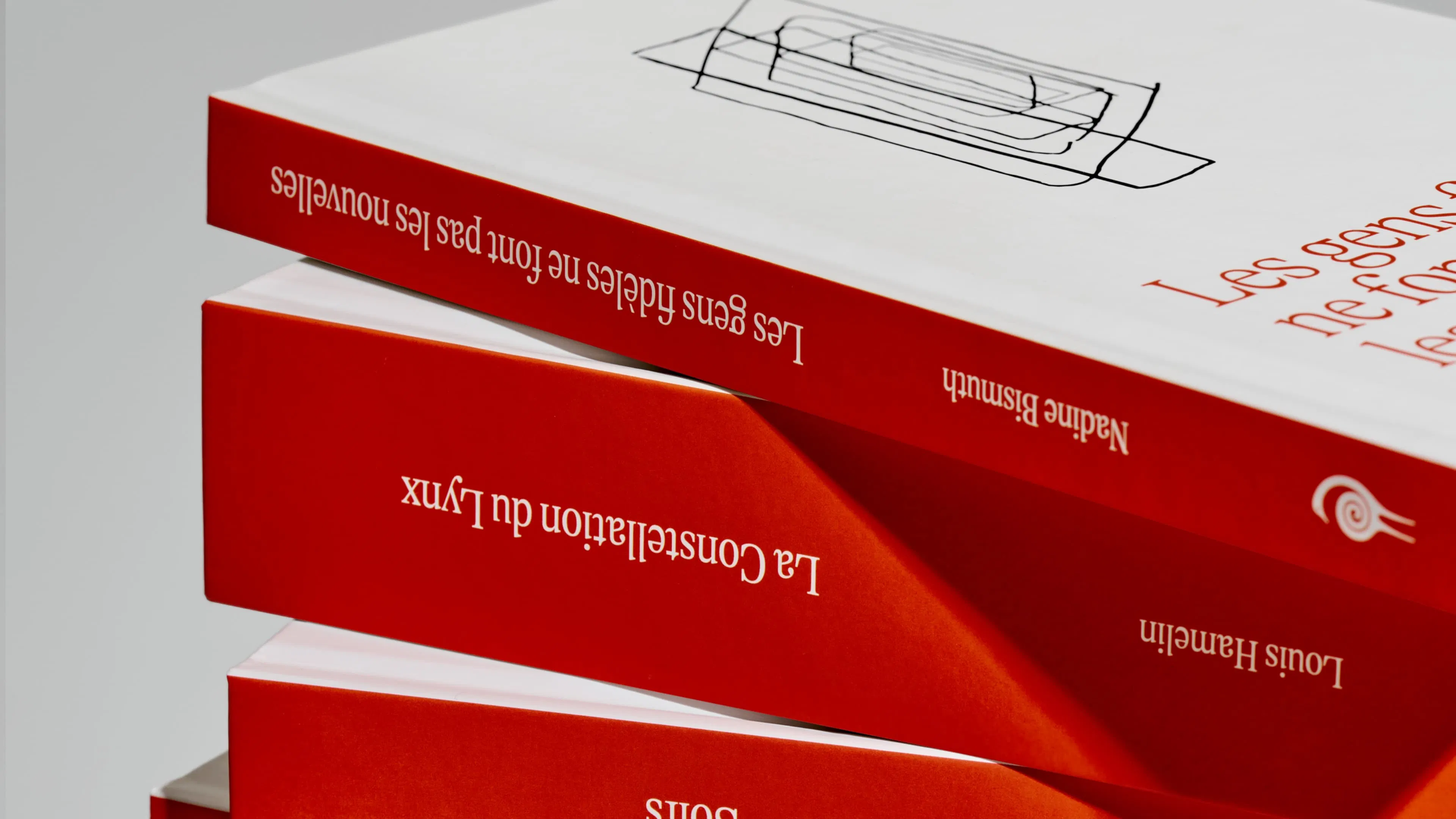Three red and white books stacked at an angle against a gray background, featuring minimalist line art on the covers.